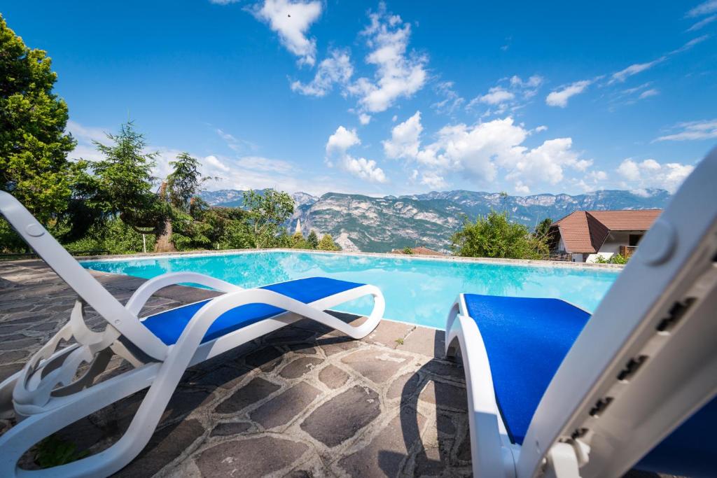 une paire de chaises assises à côté de la piscine dans l'établissement Hotel Buchholz, à Salorno