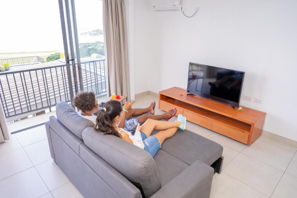 a group of people sitting on a couch watching tv at Kolibri Holiday Apartments in Victoria