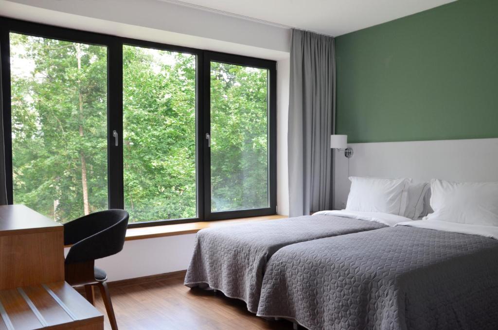 a bedroom with a bed and a desk and windows at Tip Tap Guest House in Druskininkai