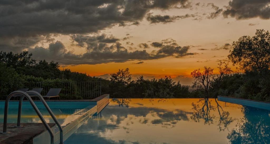 a swimming pool with a sunset in the background at Podere La Casetta - Casa di Campagna in Montaione
