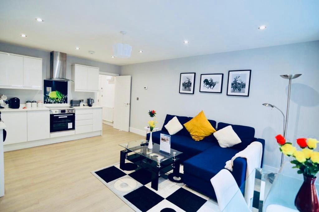 a living room with a blue couch and a kitchen at Morden Central Self Contained Flat by CozyNest in Reading