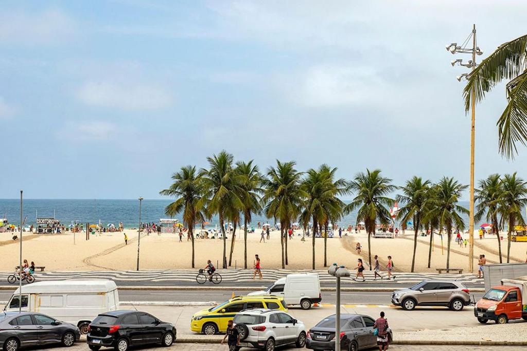 a parking lot with cars and people on the beach at Studio frente mar no Leme para 2 pessoas in Rio de Janeiro