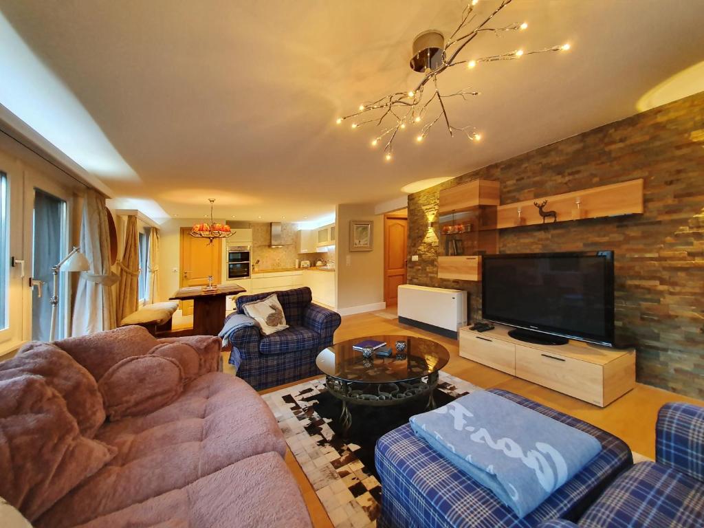 a living room with a couch and a tv at Antares in Saas-Fee