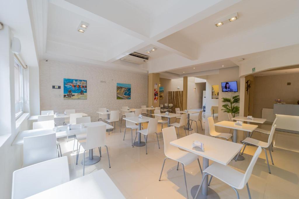 a restaurant with white tables and white chairs at Hotel Acqua in Mar del Plata