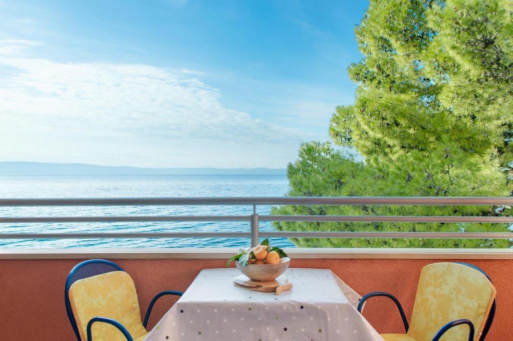 a table and chairs on a balcony with a view of the ocean at Promenada - Beachfront Apartments in Tučepi
