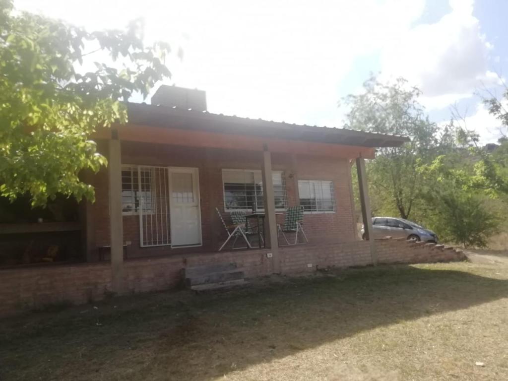 una pequeña casa con 2 sillas en el porche en El Campito casa frente al río en Villa Carlos Paz