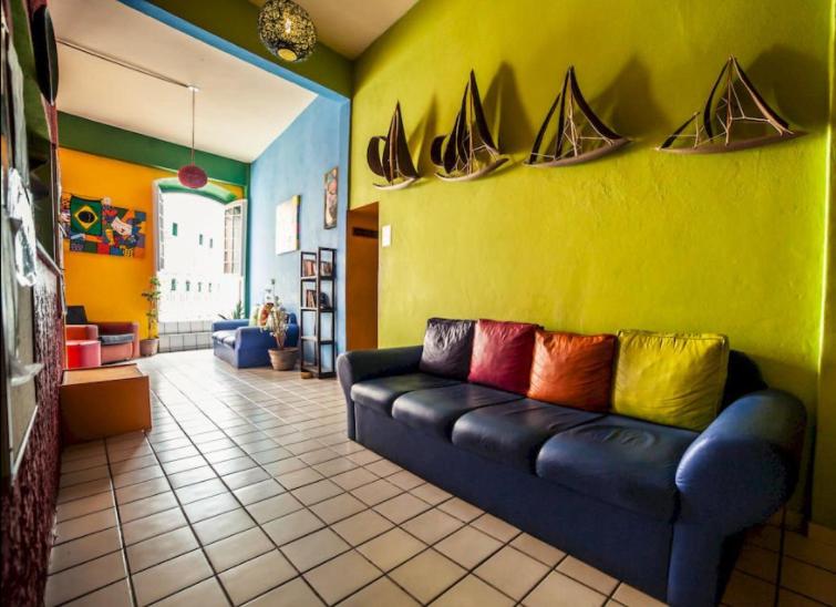 uma sala de estar com um sofá preto com almofadas coloridas em Hostel Cores do Pelô em Salvador