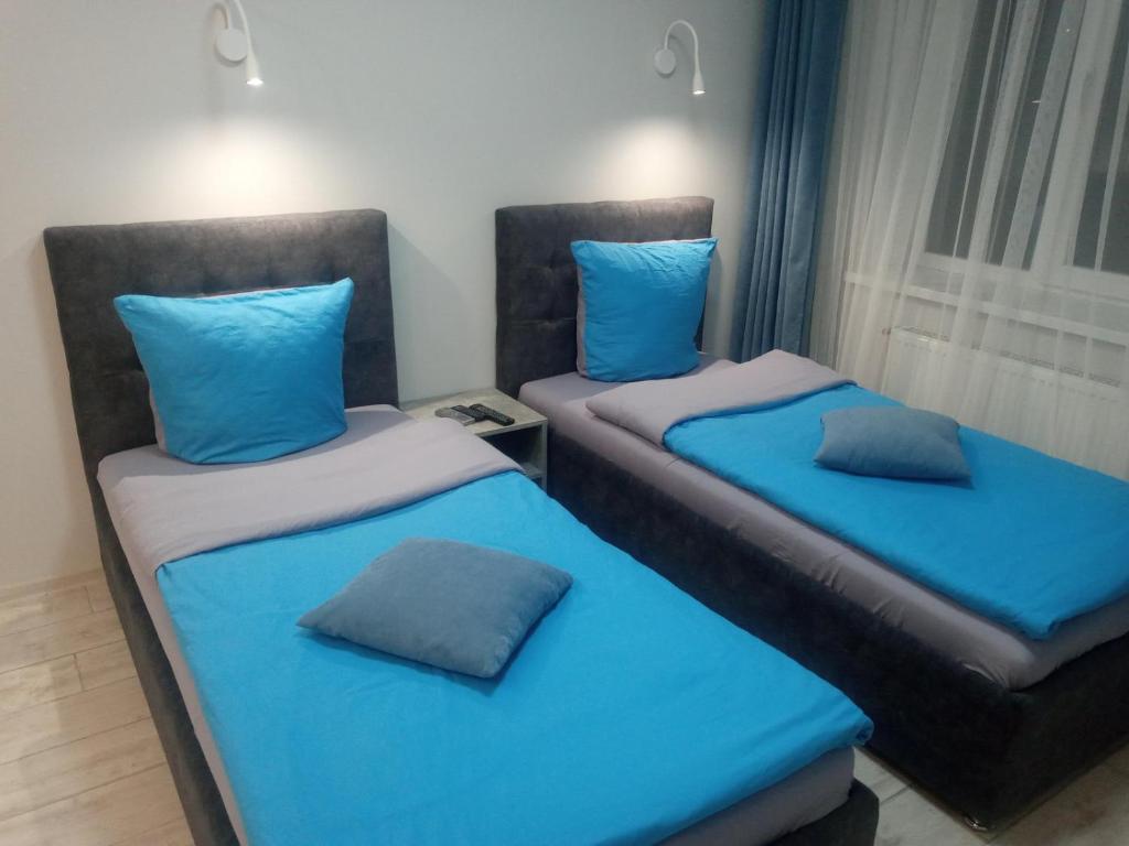 2 łóżka z niebieskimi poduszkami w pokoju w obiekcie Апартаменты Weekend Inn w mieście Użhorod