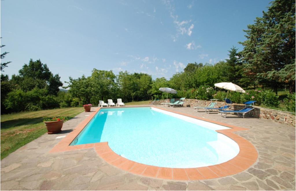una piscina in un cortile con sedie e ombrelloni di Casa vacanze Il Poggetto a Monticiano