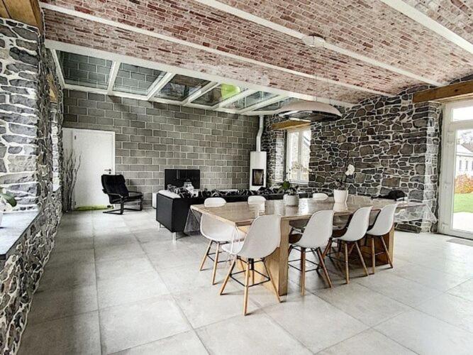 una stanza con tavolo, sedie e un muro di mattoni di Classy Holiday Home in Achet with Garden 