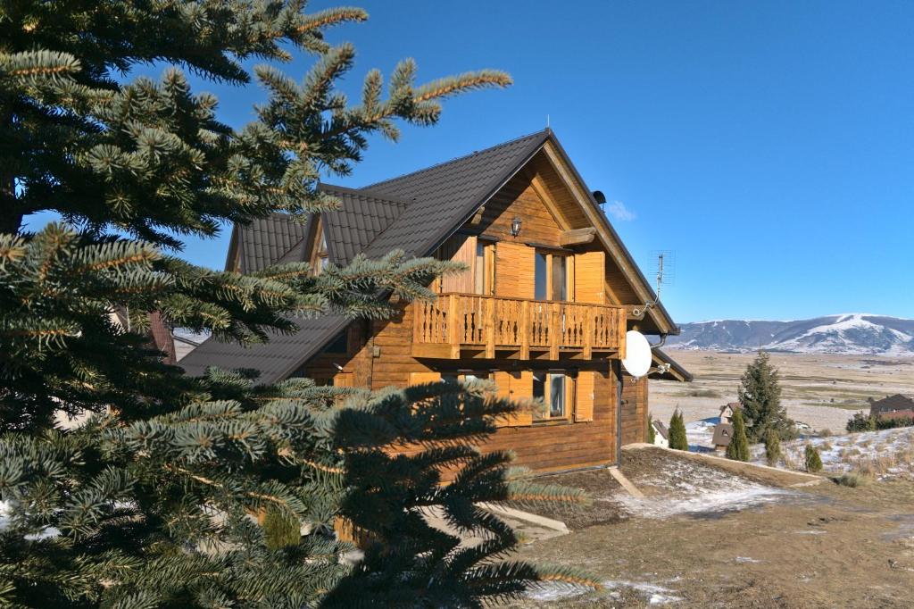 a log home with a deck on a mountain at Kiwi Chalet in Kupres