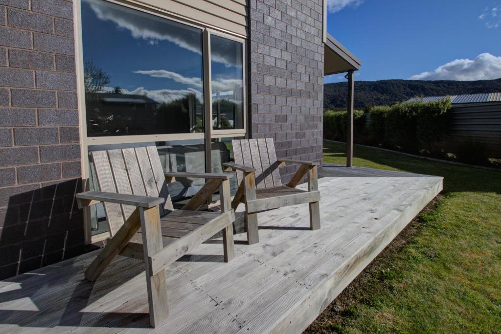 two wooden chairs sitting on a deck in front of a house at Leigh Cottage Manapouri in Manapouri