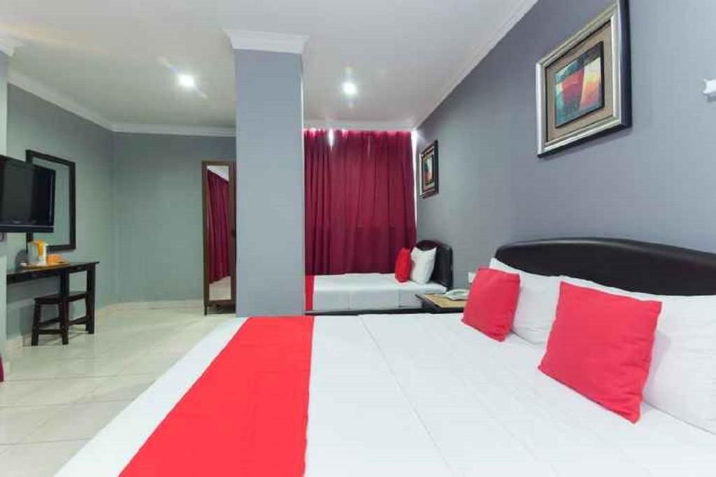 una camera da letto con un grande letto con cuscini rossi e bianchi di Puteri Ampang Hotel ad Ampang