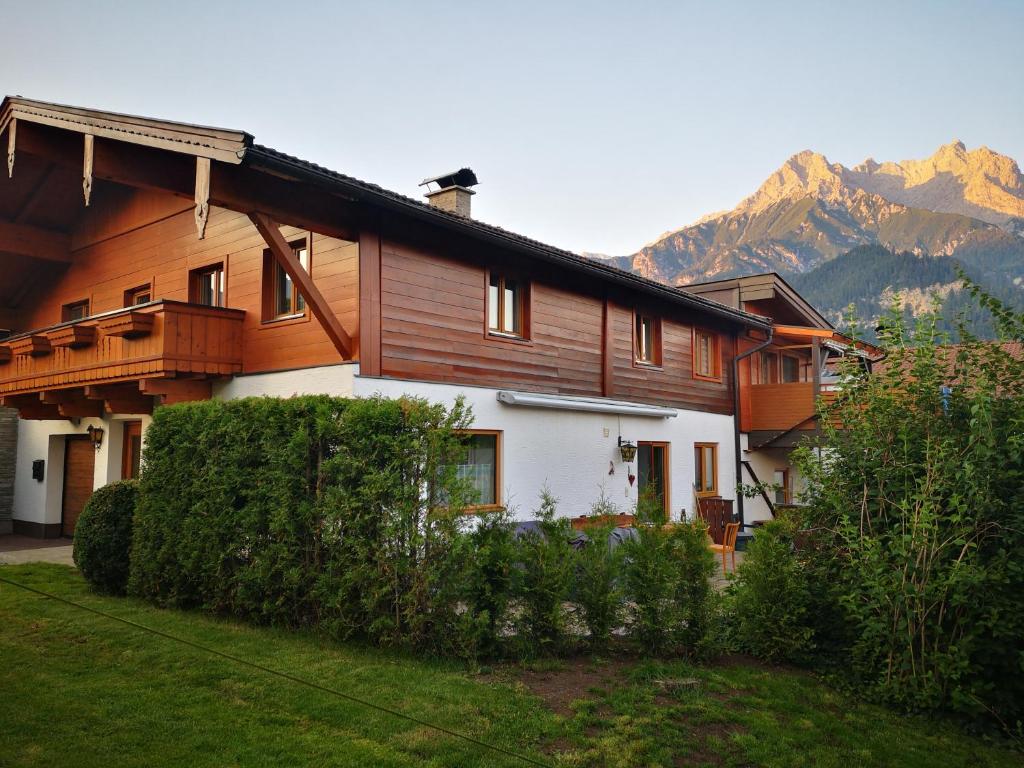 a large wooden house with mountains in the background at Haus Luxgütl in Saalfelden am Steinernen Meer