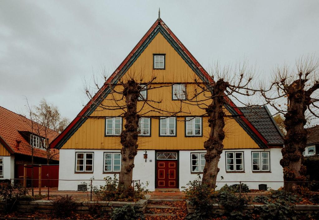 a large yellow and white house with a red door at Altes Fährhaus & Bäckerhaus (komplett) in Wewelsfleth