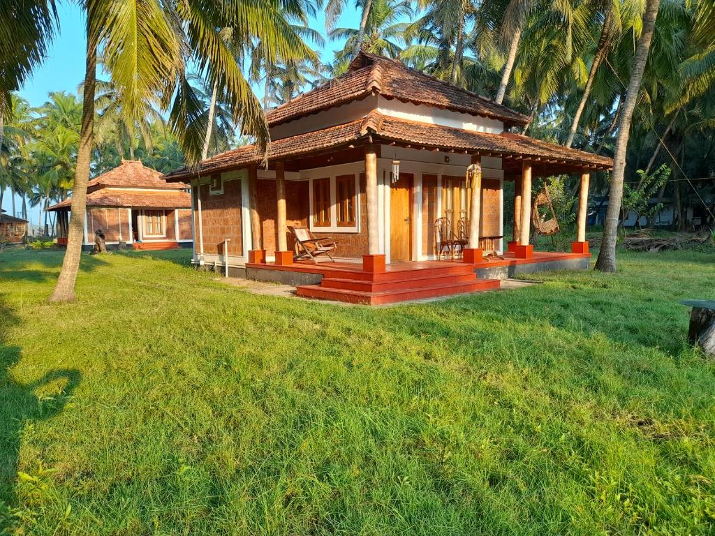 a small house in a yard with palm trees at Riverlap homestay in Nīleshwar