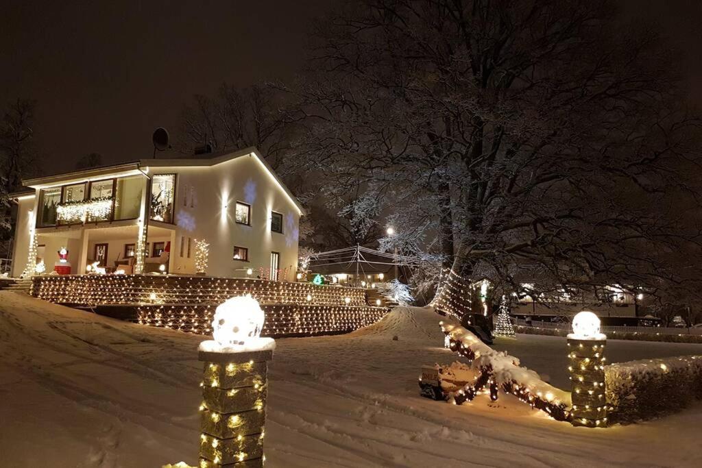 a house covered in christmas lights in the snow at Cozy apartment with garden in Stockholm