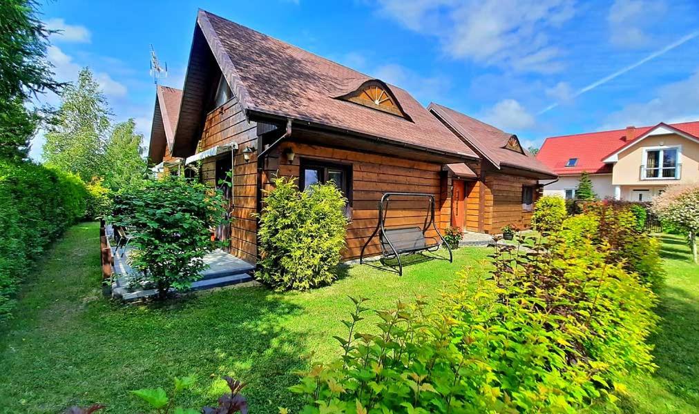 a wooden house with a porch and a yard at Morskie Chaty Platanowa in Rowy