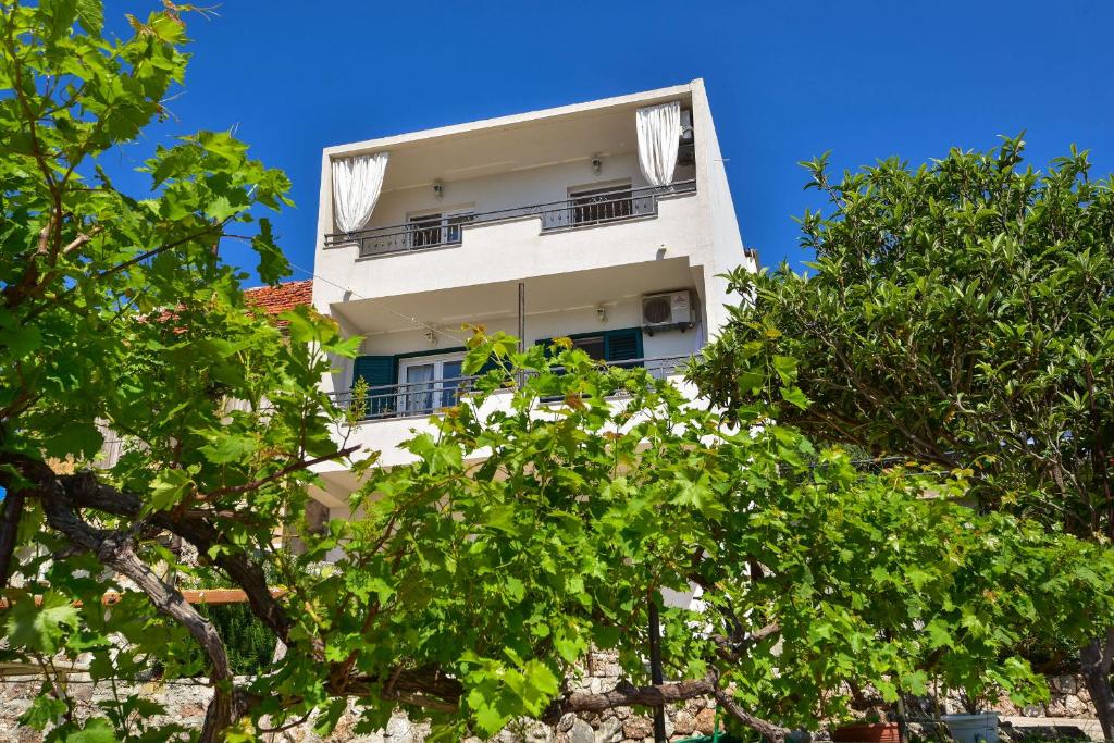 a tall white building with trees in front of it at Apartments Nina & Mili in Igrane