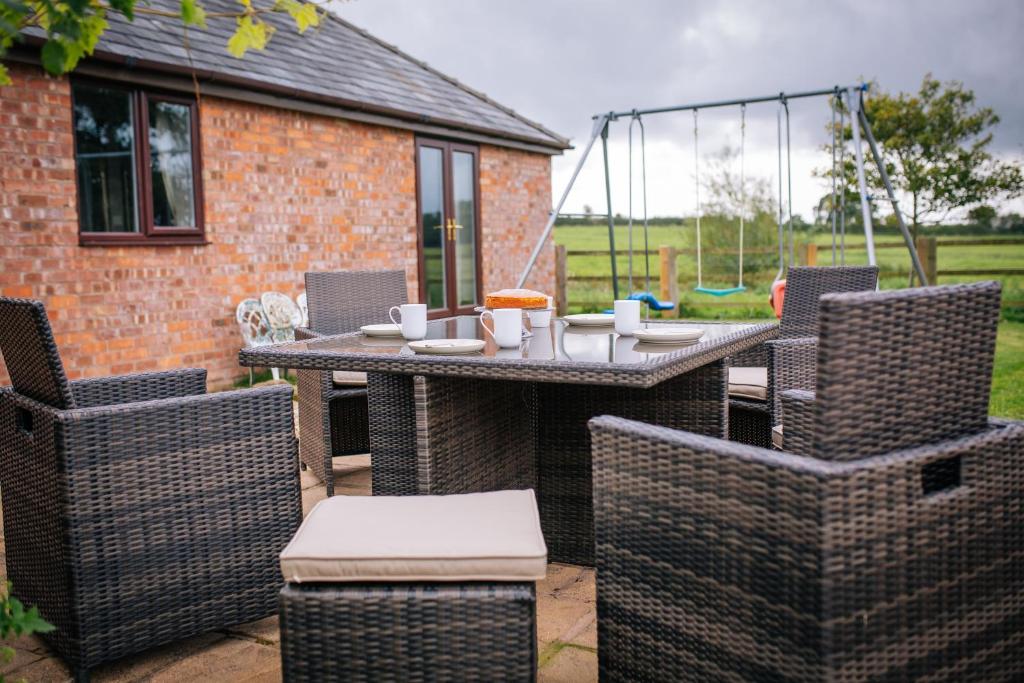 eine Terrasse mit einem Tisch und Stühlen auf einer Terrasse in der Unterkunft Millmoor Farm Holidays in Malpas