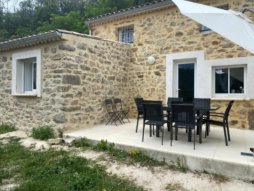 um pátio com uma mesa e cadeiras em frente a um edifício de pedra em le pavillon pierre naturelle em Jaujac