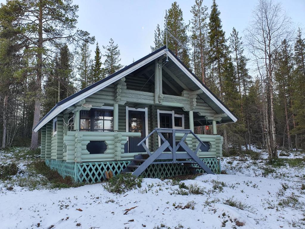 una piccola cabina verde nel bosco nella neve di Riverside Cottage near Ylläs, Lapland a Kittilä