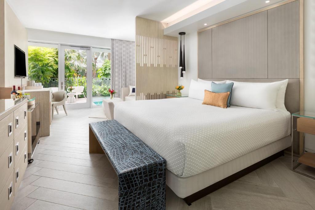 Un dormitorio con una cama grande y un banco. en H2O Suites- Adults Only en Cayo Hueso