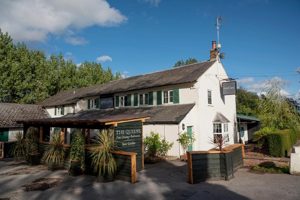 un edificio blanco con un cartel delante en The Queen's Arms, en Hungerford