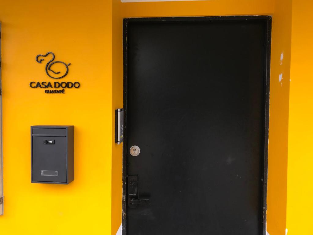 una puerta negra con un cartel en una pared amarilla en Casa Dodo Guatapé en Guatapé