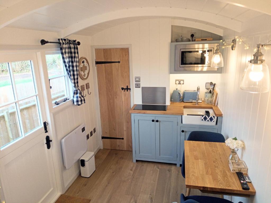 uma pequena cozinha com uma mesa e um fogão em Yew Tree View Luxury Shepherd's Hut em Sturminster Newton