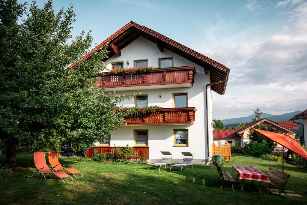 ein Haus mit einem Balkon mit Stühlen im Hof in der Unterkunft Ferienwohnungen Schmid in Lam