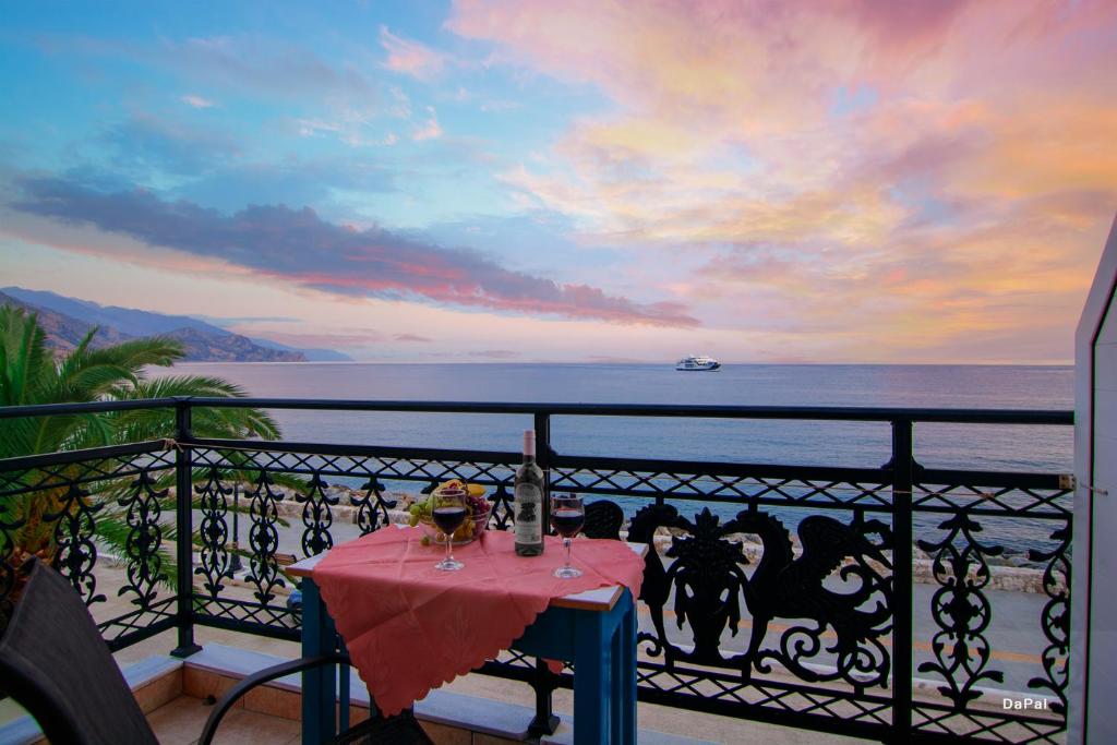 a table on a balcony with a view of the ocean at Scorpios Family Rooms in Palaiochóra