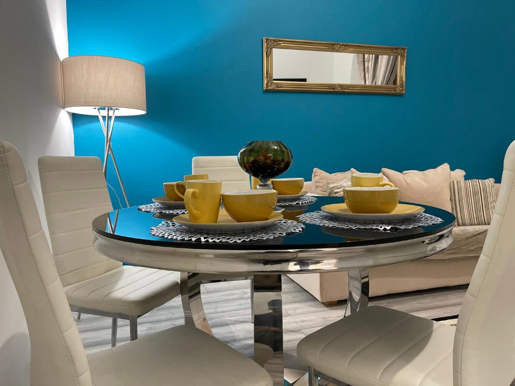 a dining room table with chairs and a blue wall at HLA KIrklee in Bellshill