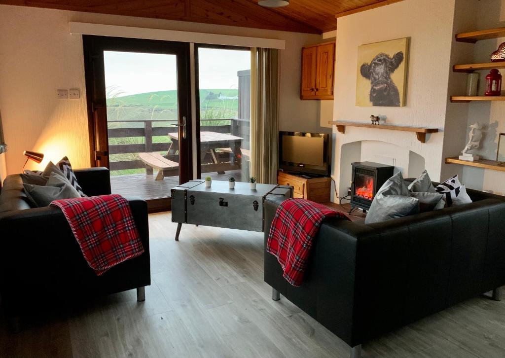 Sala de estar con 2 sofás y mesa de centro en Lodge Cabin with Fabulous Views - Farm Holiday, en Stranraer