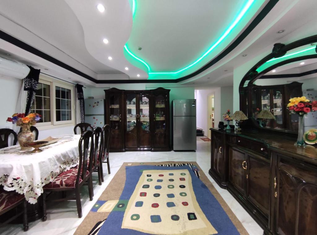 uma sala de jantar com uma mesa e uma luz verde no tecto em Luxury Apartments no Cairo