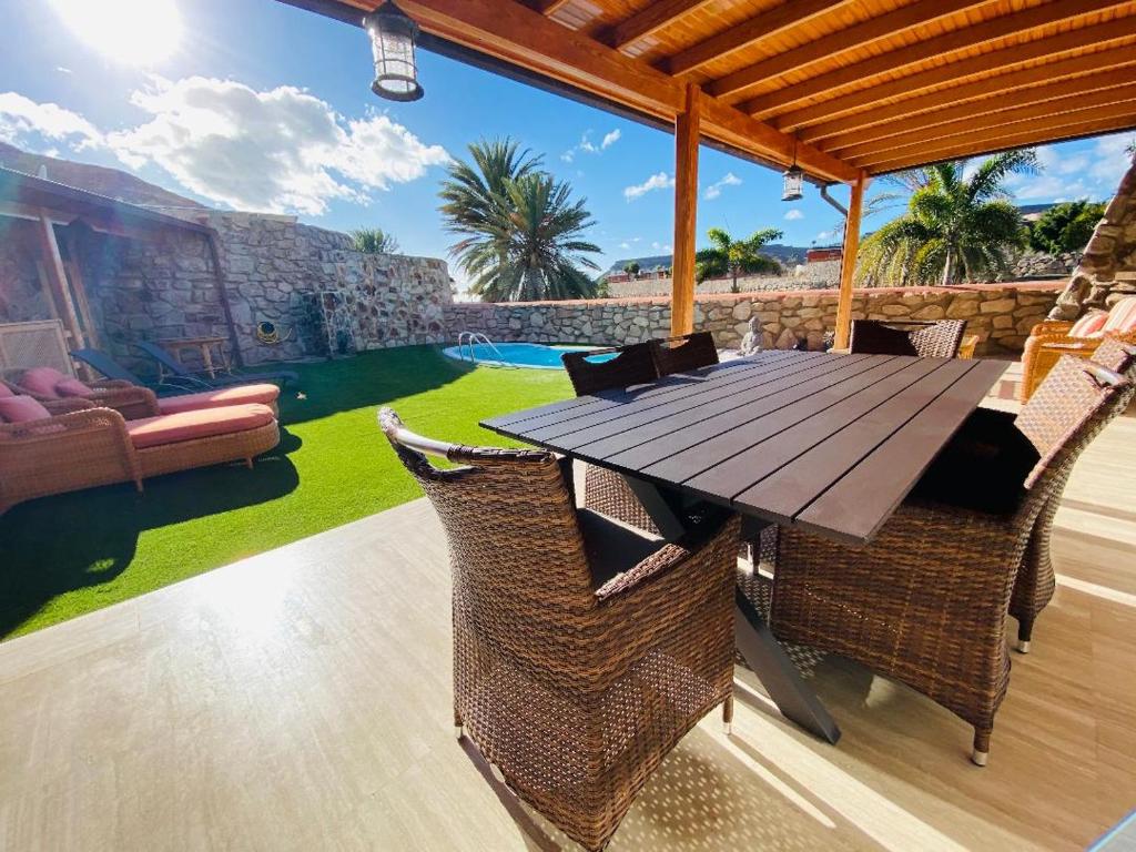 een houten tafel en stoelen op een patio bij Villa Bravo in Anfi Tauro Golf resort in Mogán