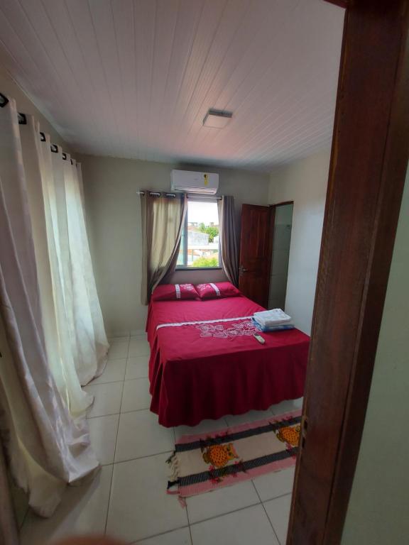 um pequeno quarto com uma cama vermelha e uma janela em Pôr do sol apartamentos em Fortaleza