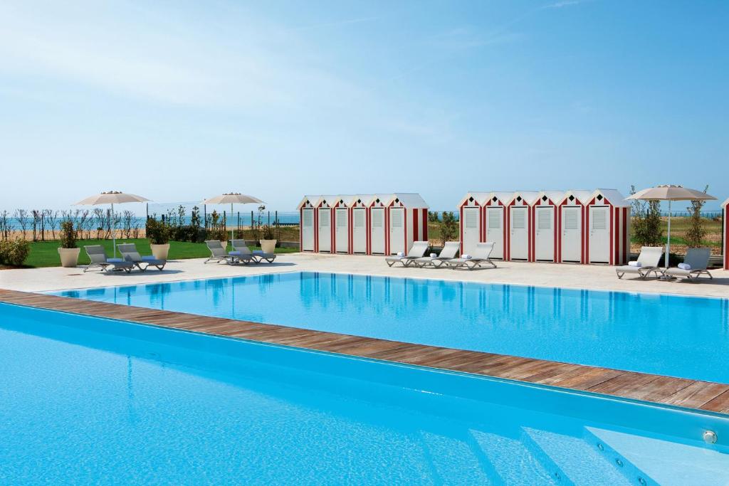 uma grande piscina com cadeiras e guarda-sóis em Adriatic Palace Hotel em Lido di Jesolo