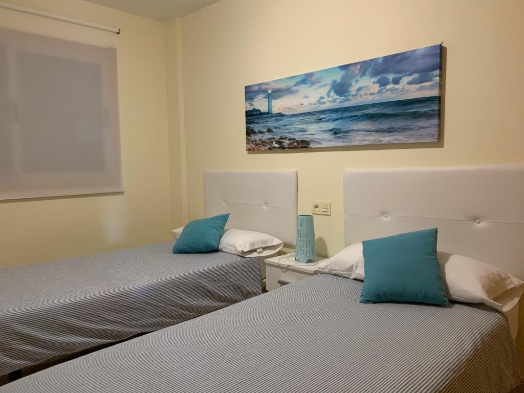 a bedroom with two beds and a painting on the wall at Maria Perla Medano in El Médano