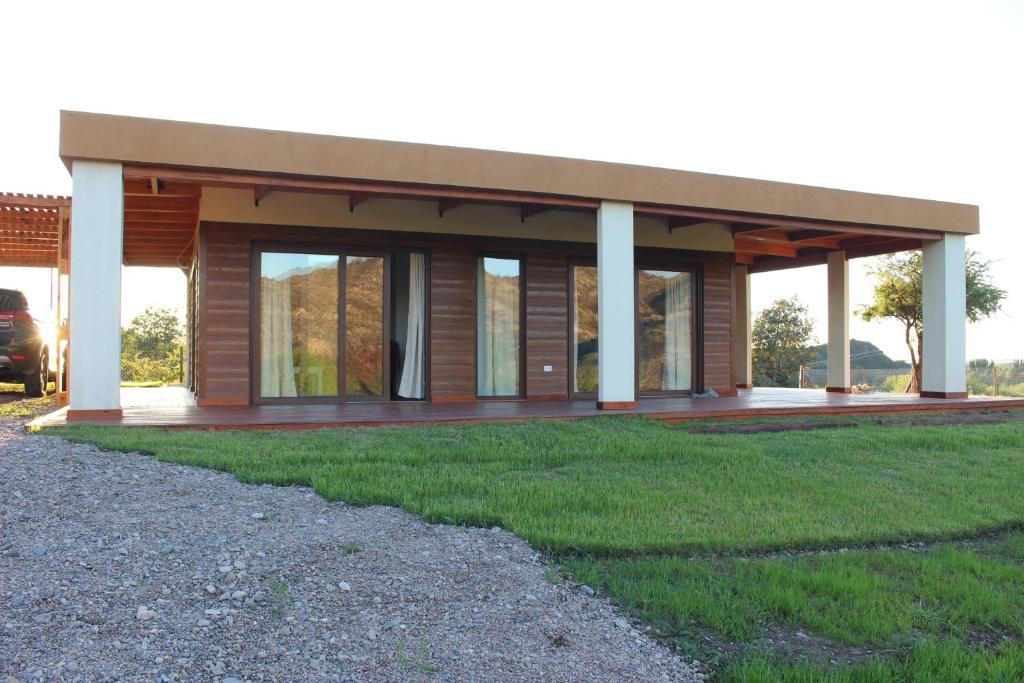 a house with a porch with a green lawn at La Encantada in Potrero de los Funes