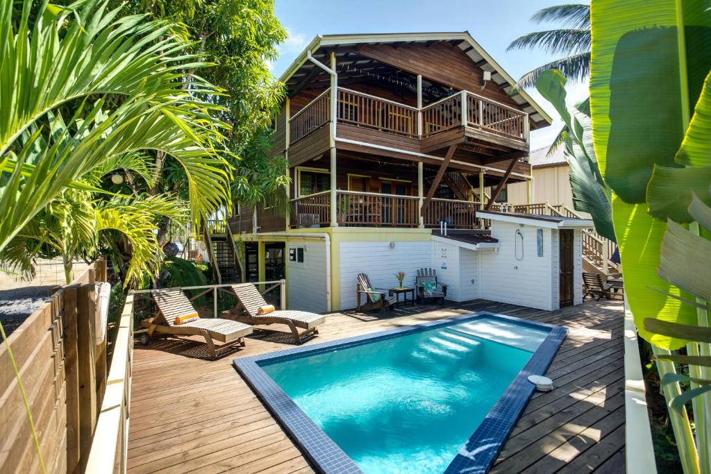 una casa con piscina frente a una casa en Driftwood Gardens Guesthouse, en Placencia Village