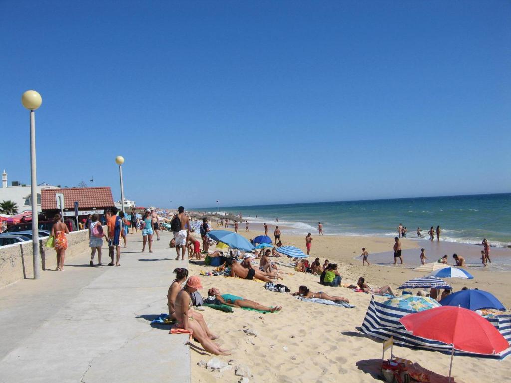 a crowd of people on a beach with umbrellas at Hotel 3K Faro Aeroporto in Faro