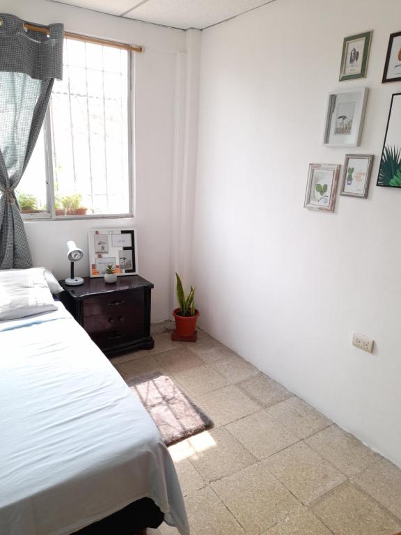 a white bedroom with a bed and a window at Casa IWANA in Guayaquil