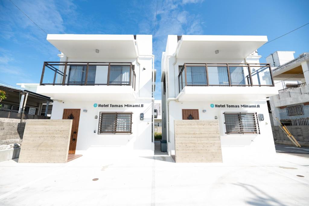 a white house with two windows on a street at ホテルトーマスみなみ in Itoman