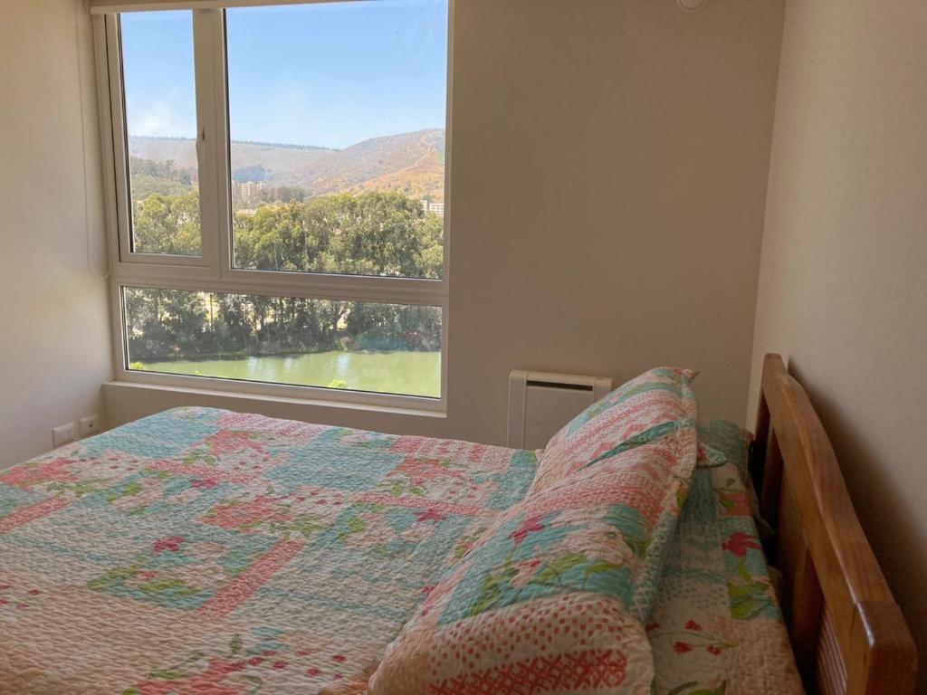 a bedroom with a bed and a large window at Departamento Papudo Laguna Vista al Mar y Laguna in Papudo