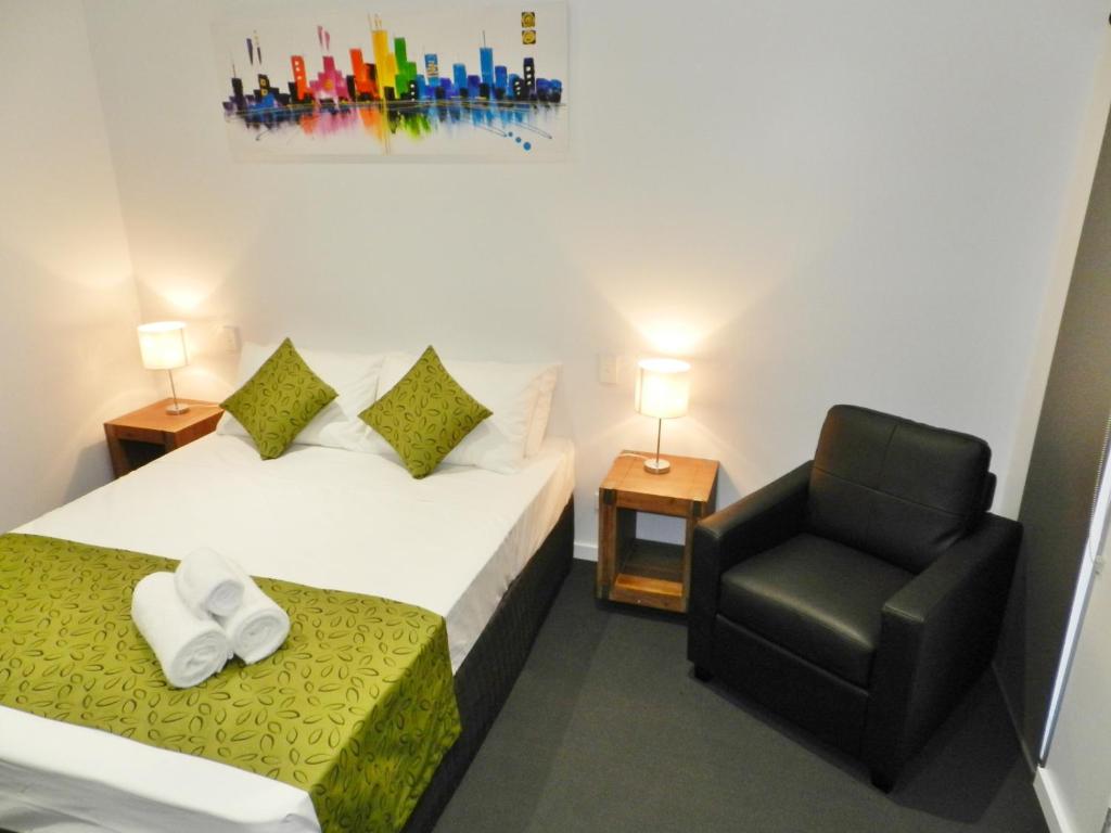 una habitación de hotel con 2 camas y una silla en Copper City Motel, en Mount Isa