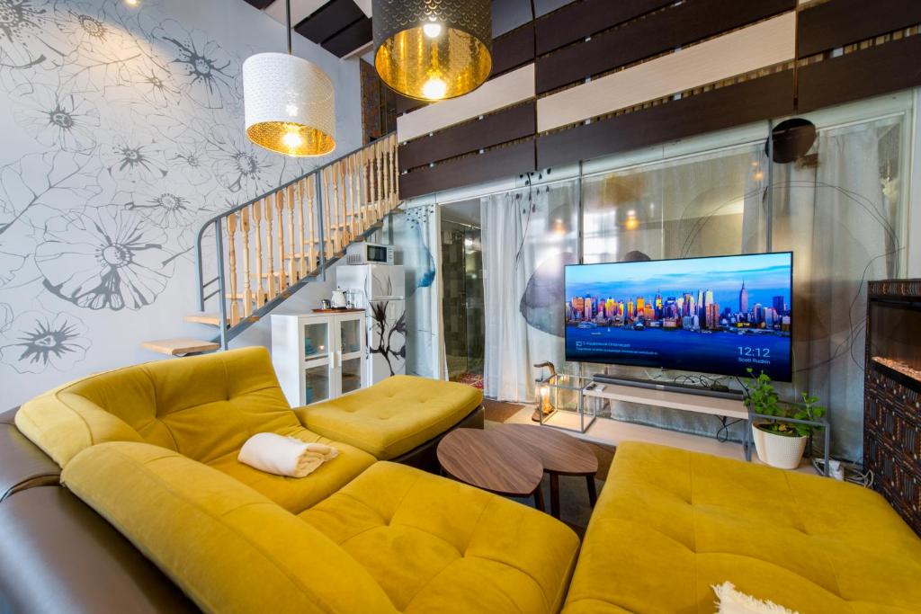 Inn OZZ في كاراغاندي: غرفة معيشة مع أريكة صفراء وتلفزيون