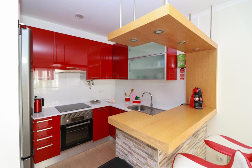 cocina con armarios rojos y encimera de madera en Parede Flats, en Parede