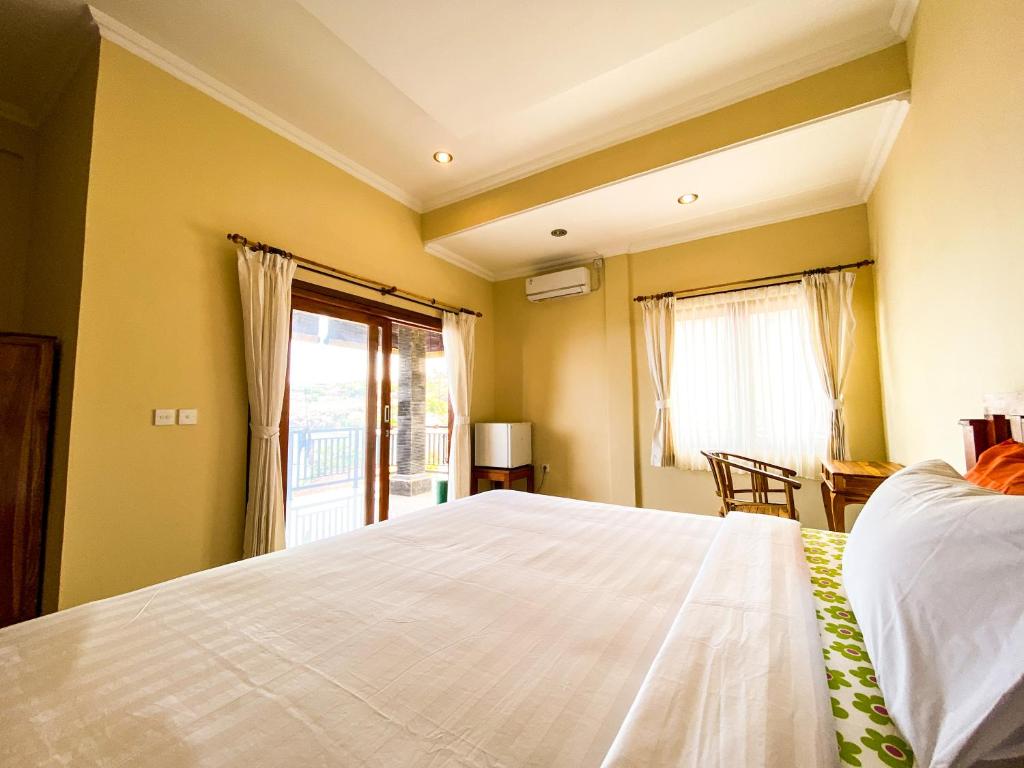 a bedroom with a large white bed and a window at Diver's Cafe Amed in Amed