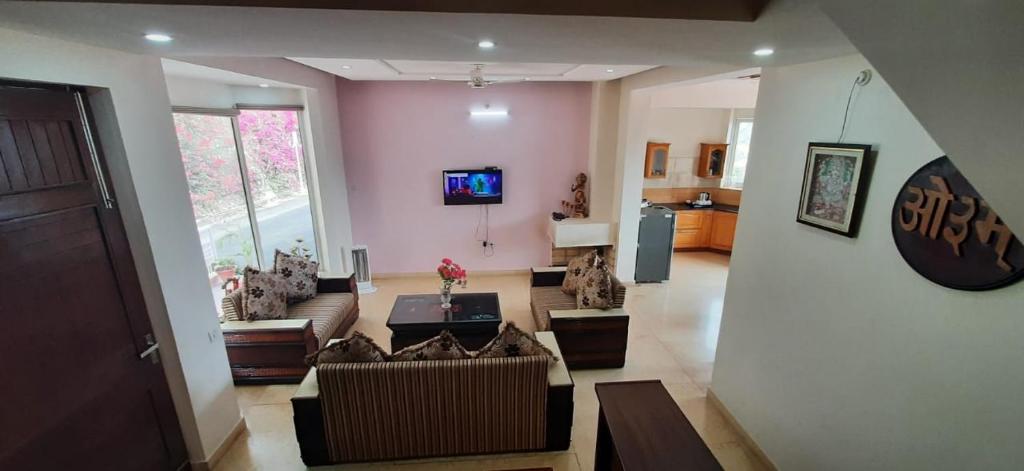 uma sala de estar com sofás e uma televisão na parede em amravati resort em Solan